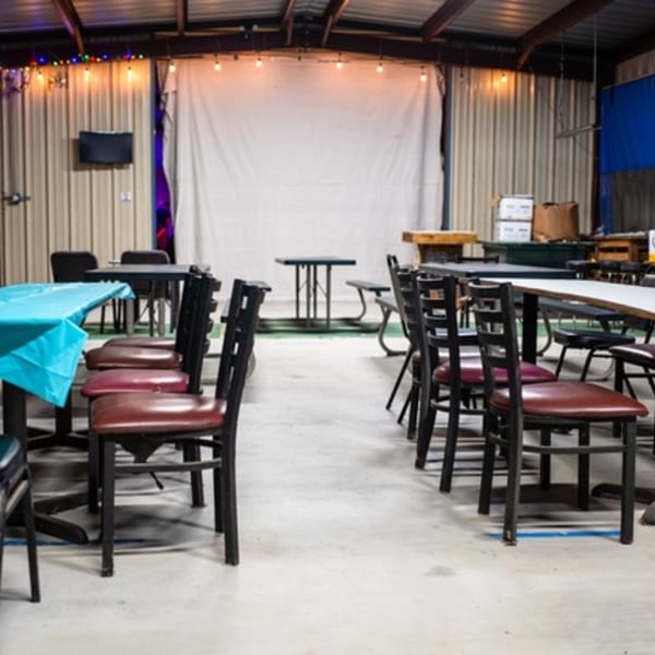 Interior of Goofy's Grill with rows of tables and chairs, string lights, and a large white screen.
