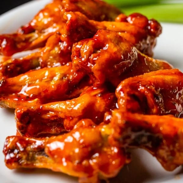 Close-up of Goofy's Grill's chicken wings, coated in a glossy, vibrant orange sauce.