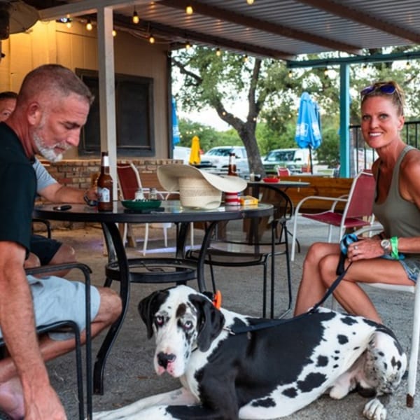 Patrons and a large dog relaxing on the outdoor patio of Goofy's Grill.