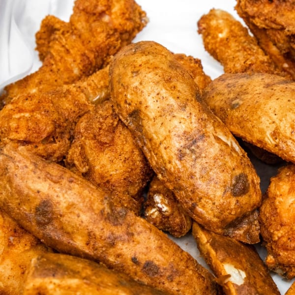 Close-up of golden-brown fried chicken and potato wedges from Goofy's Grill.