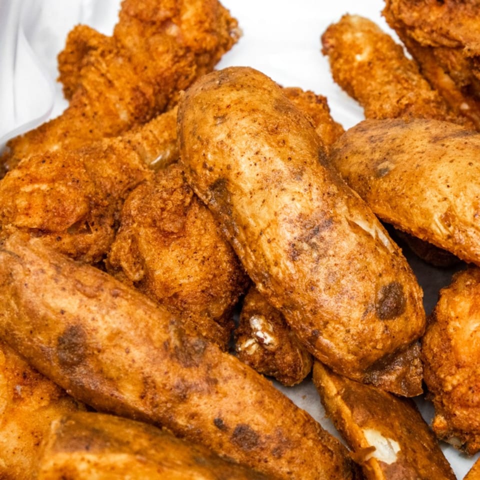 Close-up of golden-brown fried chicken and potato wedges from Goofy's Grill.